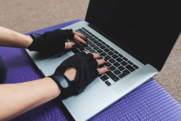 笔记本电脑上戴黑色运动手套的手